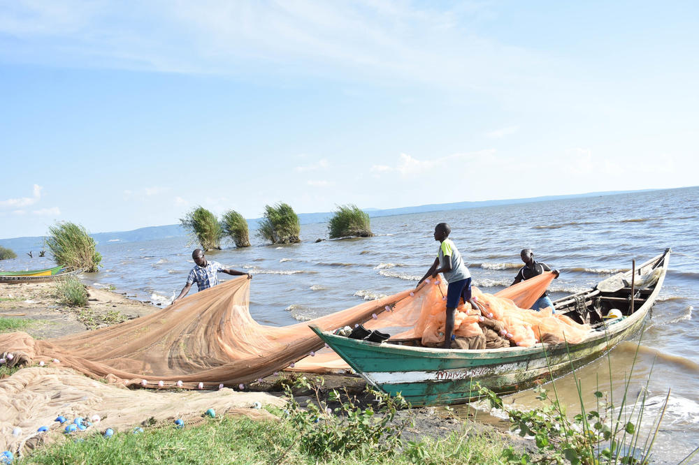 Fishing nets are an important — and expensive — part of the fishing business. Above: Fishermen get some help from local kids preparing nets before a fishing expedition on Lake Victoria.
