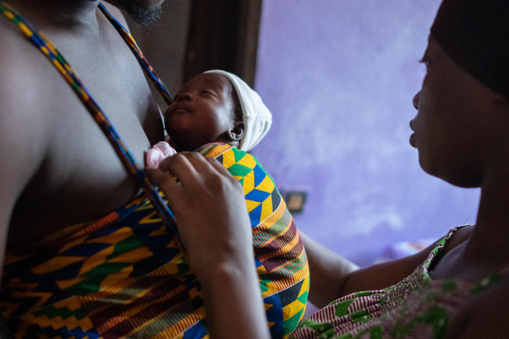 At home with a newborn daughter, Abuwa Kristien helps her husband, Kubyes Abuwaka, hold the child in the kangaroo care position. 