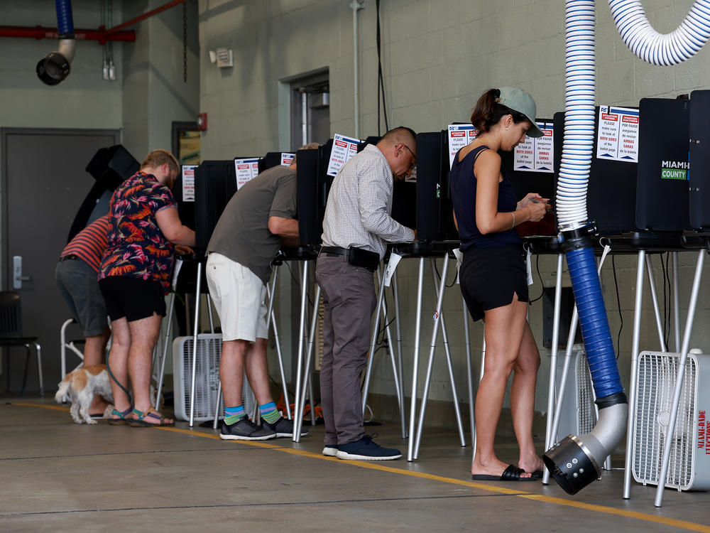 Voters cast their ballots at a polling station set up in a fire station on Aug. 23 in Miami Beach, Fla.