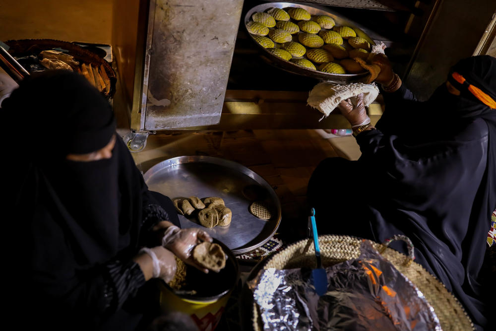 Um Abdullah (right) and her granddaughter Hajer bake <em>klaija</em> — a waffle-like biscuit stuffed with date molasses — in Buraydah on Aug. 3, 2022. The duo are known around the city for their highly sought-after <em>klaijas</em>.