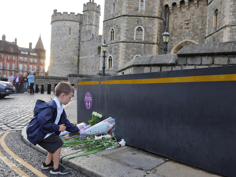 Queen Elizabeth II's death sets a succession apparatus in motion that has been dormant for decades. Here, a youngster leaves flowers outside Windsor Castle on Thursday.