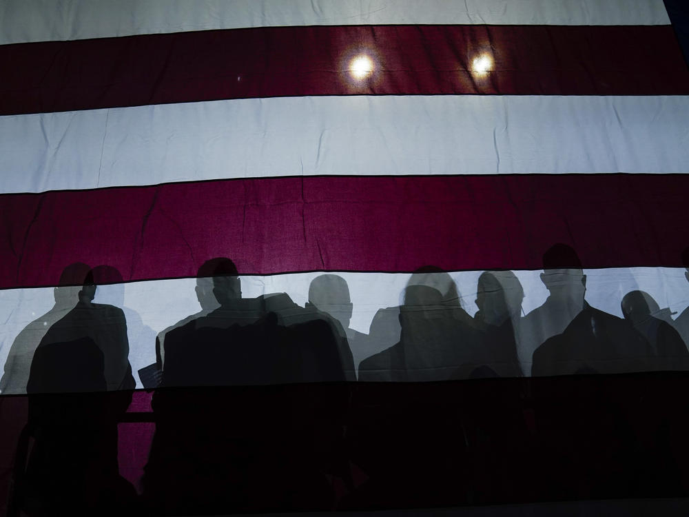 Silhouettes of people are seen on an American flag as President Joe Biden speaks on July 6, 2022, in Cleveland.