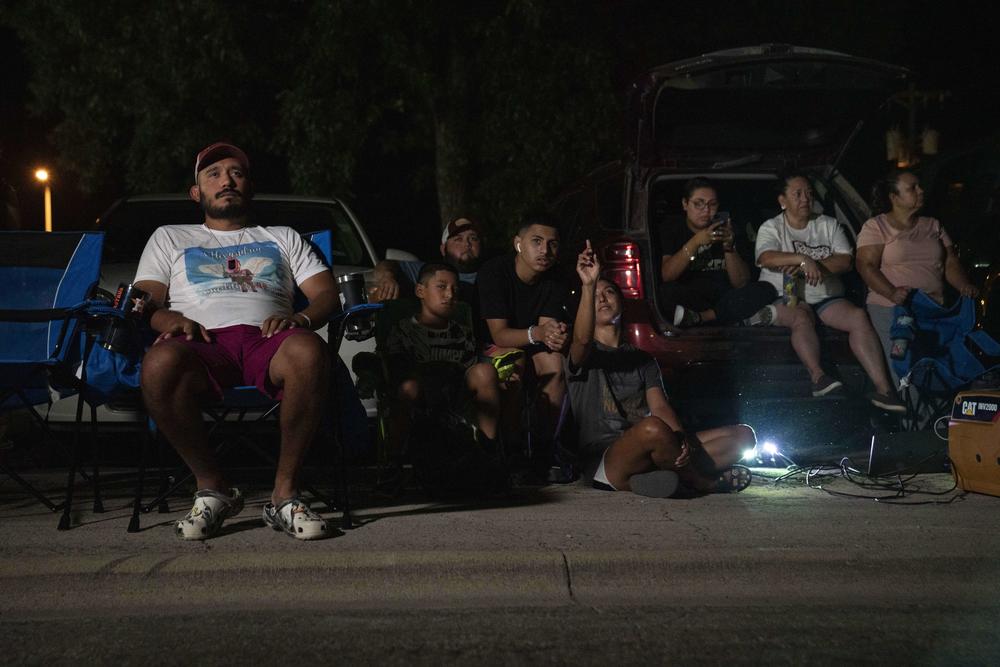 La familia y los amigos de Lexi observan cómo se forma el mural.