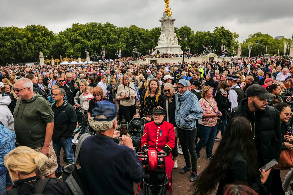 Well-wishers, including a Chelsea Pensioner, gather outside Buckingham Palace, on Friday, the first day of public mourning following the death of Queen Elizabeth II.