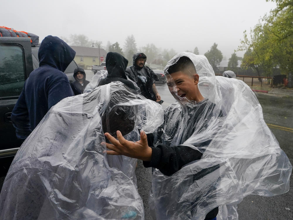 Members of the Ornelas family put on plastic raincoats as wind and rain pummel the area Friday, Sept. 9, 2022, in Julian, Calif. A tropical storm nearing Southern California has brought fierce mountain winds, high humidity, rain and the threat of flooding to a region already dealing with wildfires and an extraordinary heat wave. (AP Photo/Gregory Bull)