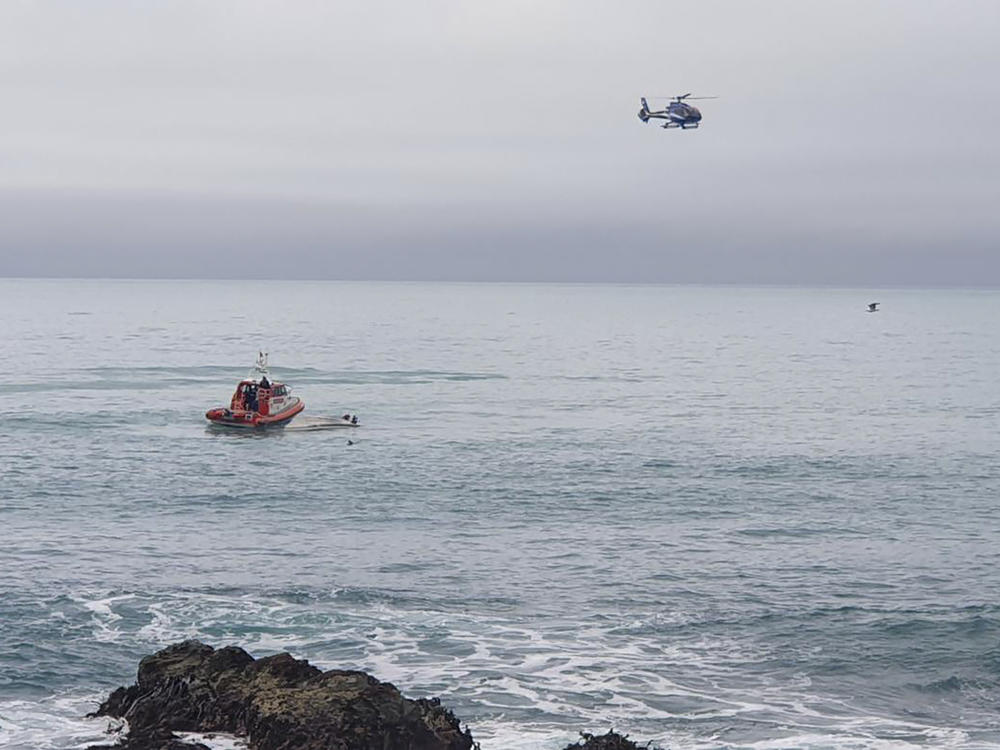 A helicopter and a rescue boat search for survivors off the coast of Kaikoura, New Zealand, on Saturday.