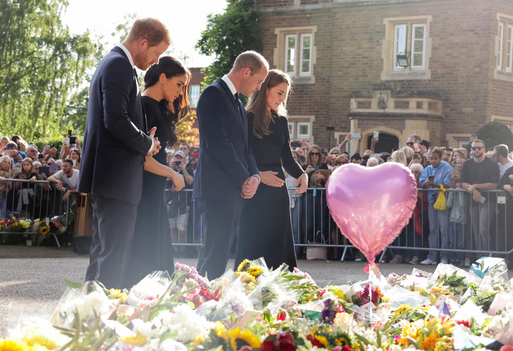 Prince Harry, Duke of Sussex (from left), Meghan, Duchess of Sussex, Prince William, Prince of Wales and Catherine, Princess of Wales look at floral tributes left by members of the public for the late Queen Elizabeth II on the Long walk at Windsor Castle on Saturday.