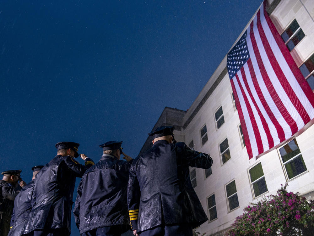 First responders salute in a driving rain as a U.S. flag is unfurled at the Pentagon on Sunday, the 21st anniversary of the 9/11 attacks.
