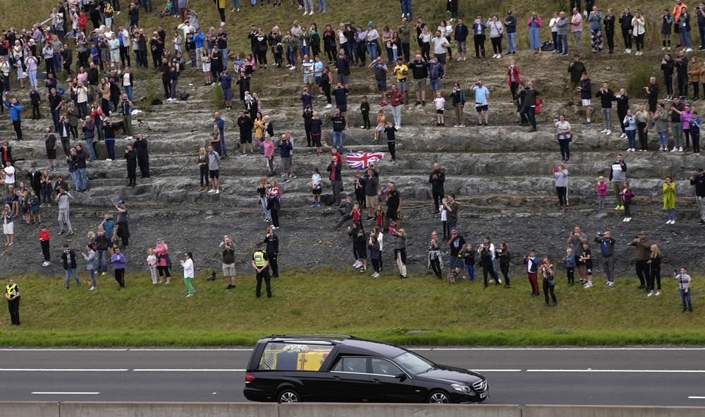 Spectators watch as the cortege with the hearse carrying the coffin of Queen Elizabeth II drives on the M90 motorway as it makes its journey to Edinburgh from Balmoral in Scotland.