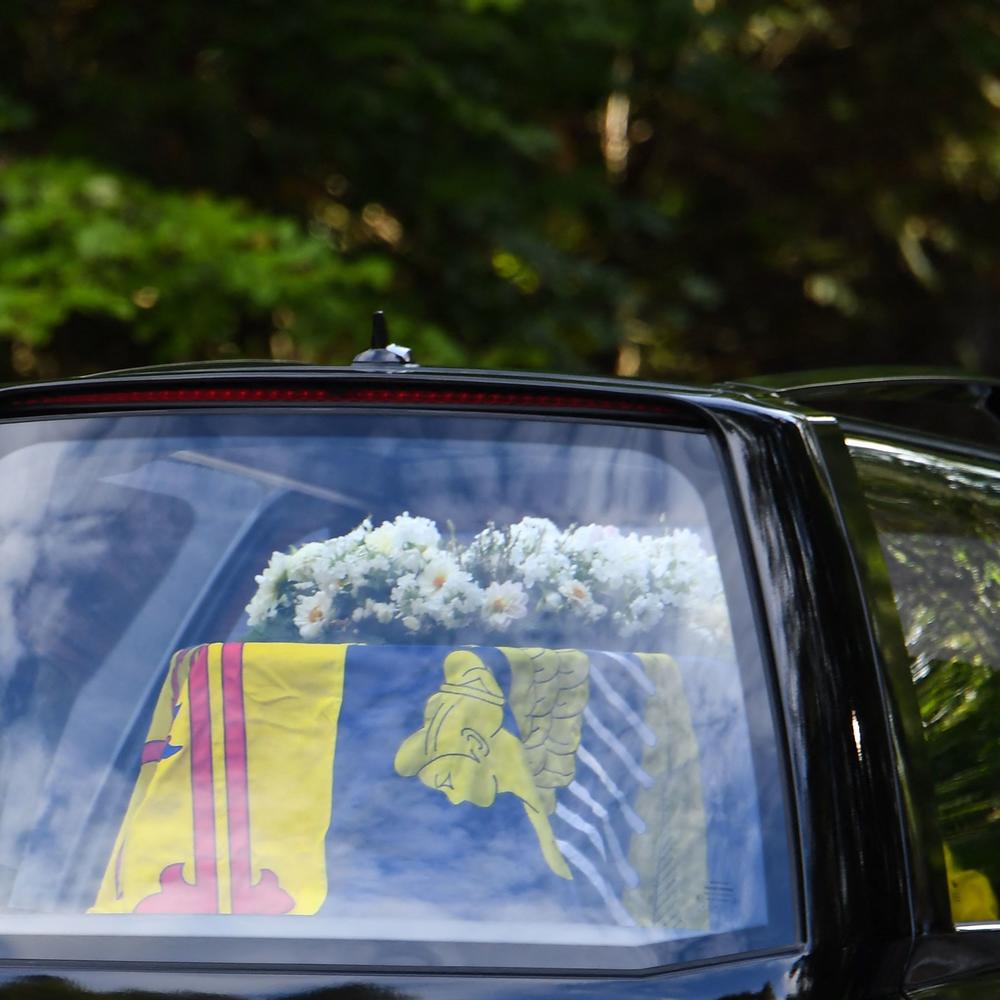 The hearse carrying the coffin of Queen Elizabeth II, which is covered with the Royal Standard of Scotland and flowers, is driven away from Balmoral Castle in Ballater.