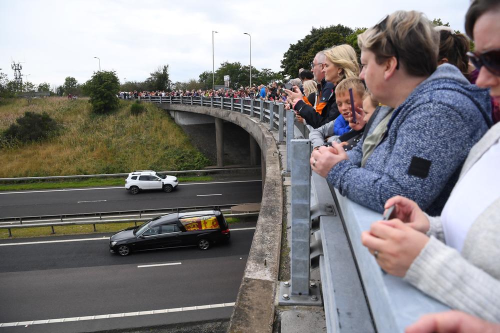 Members of the public stand on a bridge, in Kinross, overlooking the M90 motorway, to pay their respects as they look at the hearse carrying the coffin of Queen Elizabeth II.