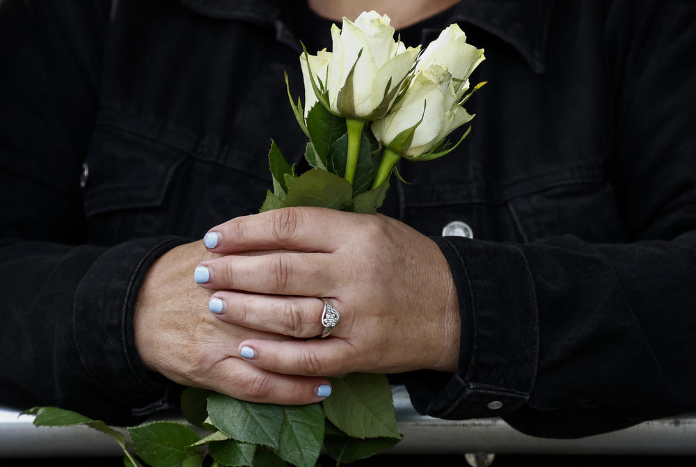 People hold flowers as they wait to view the cortege carrying the coffin of the late Queen Elizabeth II in Ballater, Scotland.