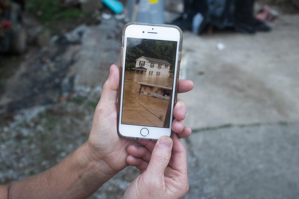 Derena Dunbar shows a cell phone photo of her father's home damaged during the recent flood in Millstone, Ky.