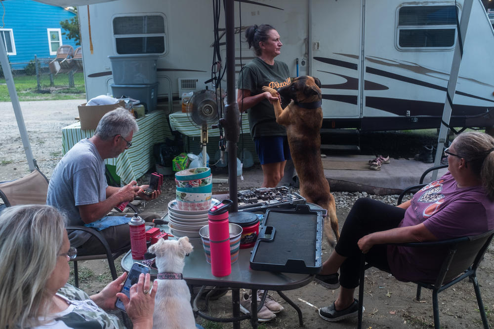 Mary Baker, Dino McBee, Gina Tryee, and Melissa McBee rest outside of the camper where some of them are staying due to damage to their homes in recent flooding.
