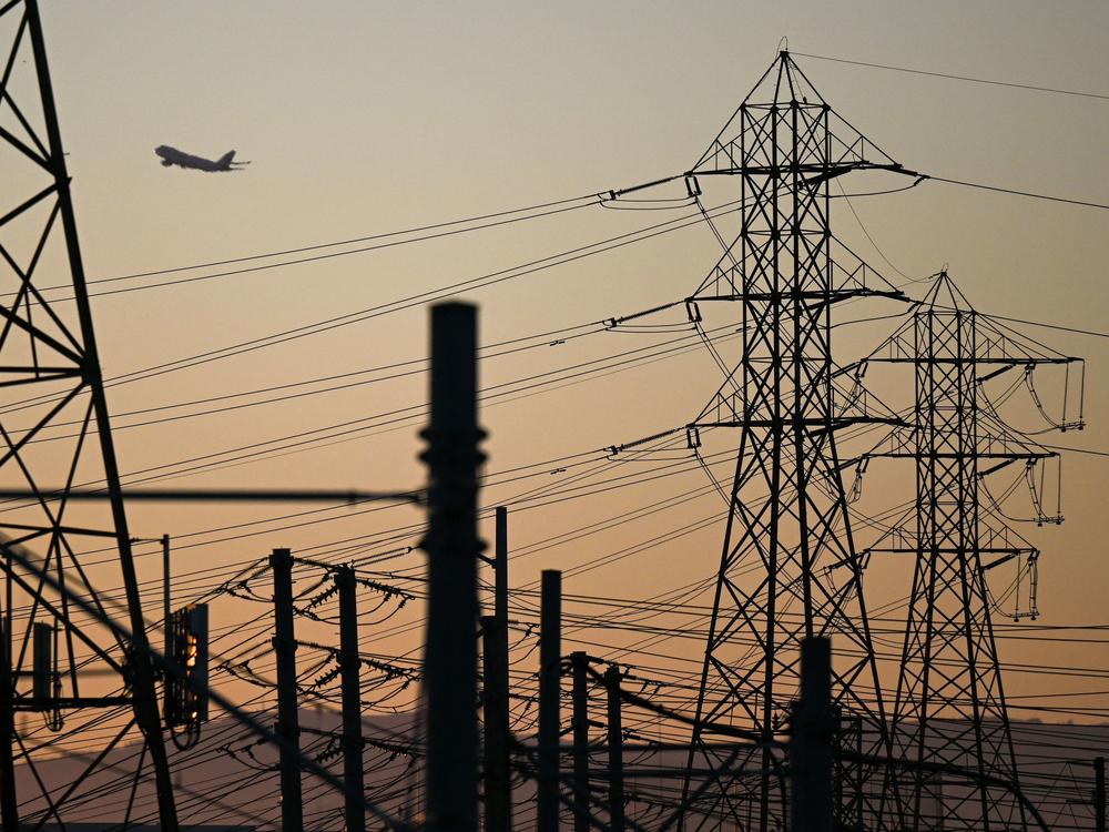 An aircraft takes off from Los Angeles International Airport (LAX), with electric power lines visible at sunset as the California Independent System Operator announced a statewide electricity Flex Alert urging conservation to avoid blackouts in El Segundo, Calif., on Aug. 31.