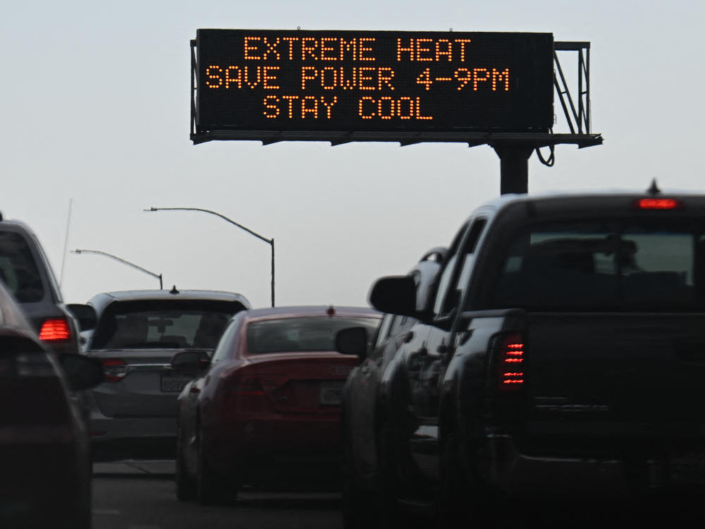 Vehicles drive past a sign on the 110 Freeway warning of extreme heat and urging energy conservation during a heat wave in downtown Los Angeles on Sept. 2. Soaring electricity bills are pinching many household budgets across the country even as gasoline prices have come down.