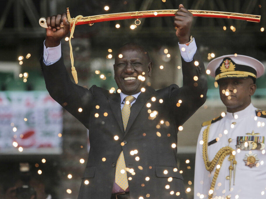 Kenya's new president William Ruto, seen Tuesday behind fountain fireworks, holds up a ceremonial sword as he is sworn in to office at a ceremony held at Kasarani stadium in Nairobi.