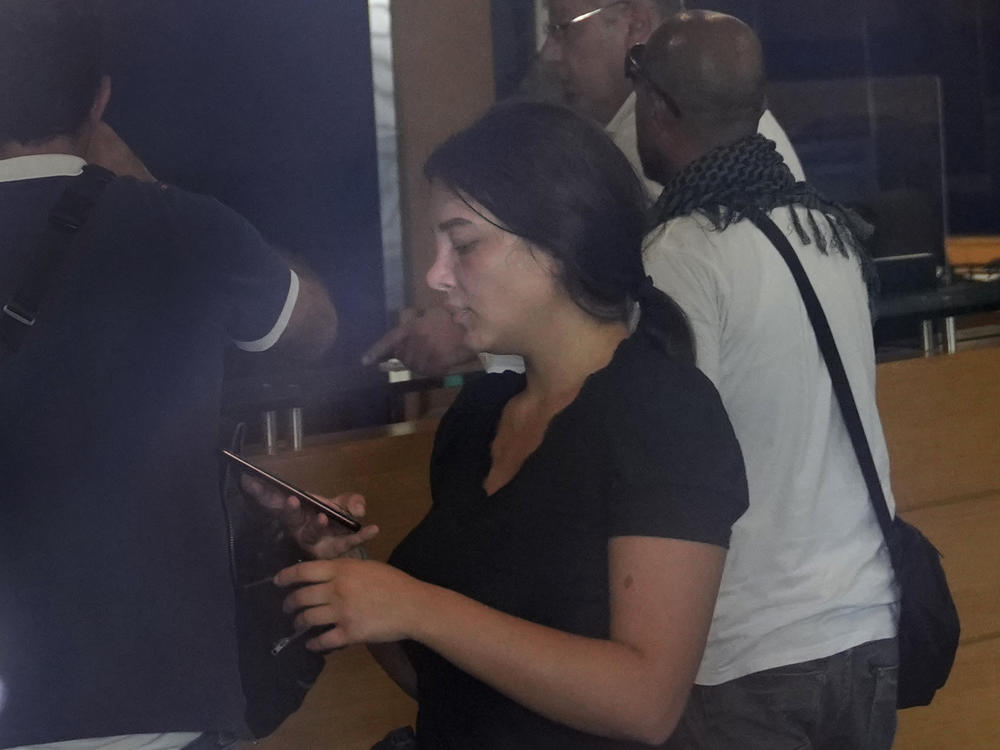 Sali Hafez (center), accompanied by activists, looks at her phone on Wednesday after breaking into a BLOM Bank branch in Beirut, Lebanon, brandishing what she later said was a toy pistol and taking $13,000 from her trapped savings account.