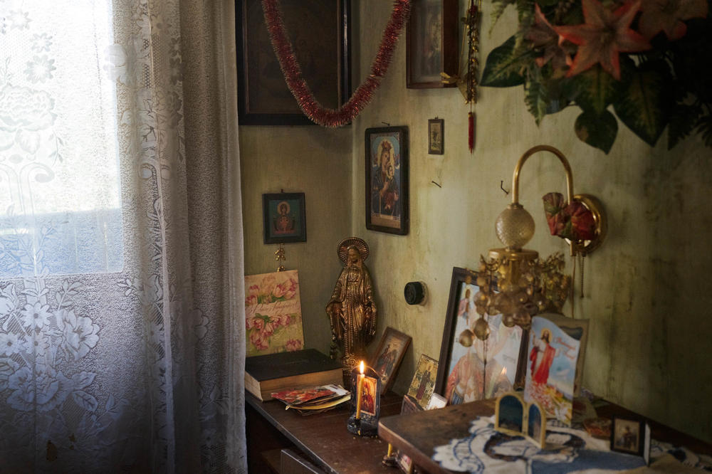 A lit candle sits in an altar in a corner of Anna's home. She prays for peace to come.