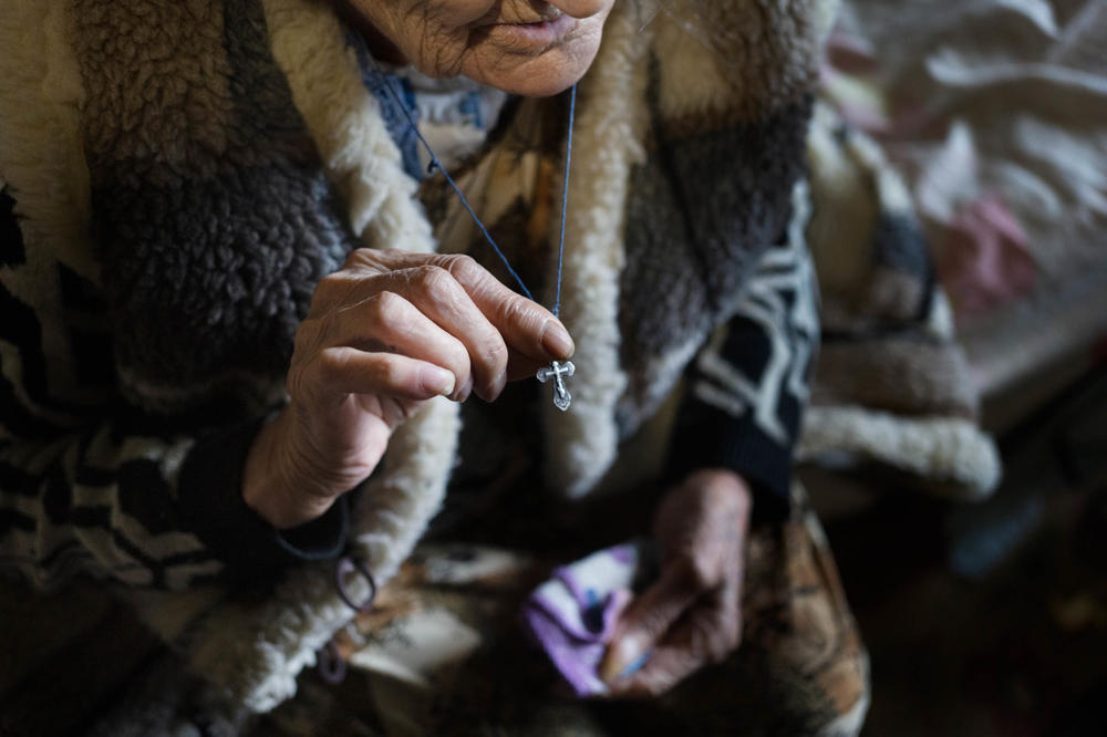 Anna, 86, shows the cross she wears around her neck.