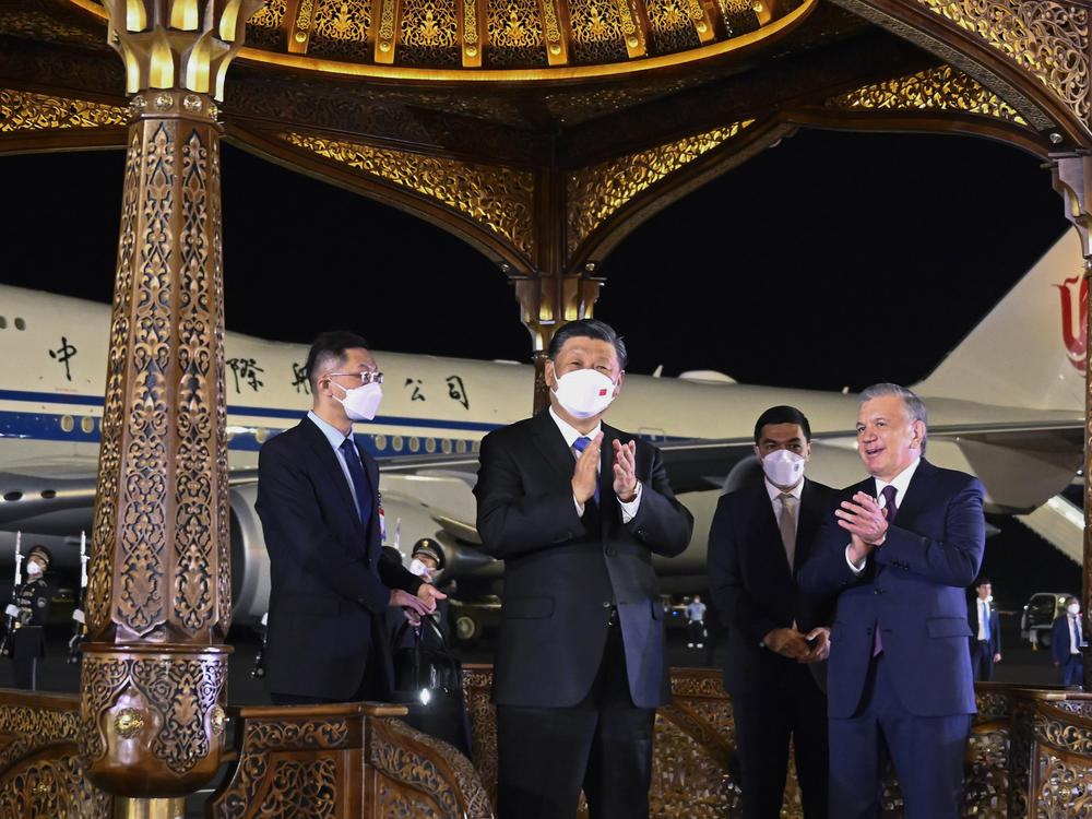 In this photo released by Xinhua News Agency, Chinese President Xi Jinping, center, is welcomed by Uzbekistan President Shavkat Mirziyoyev, right, as he arrives in Samarkand, Uzbekistan.