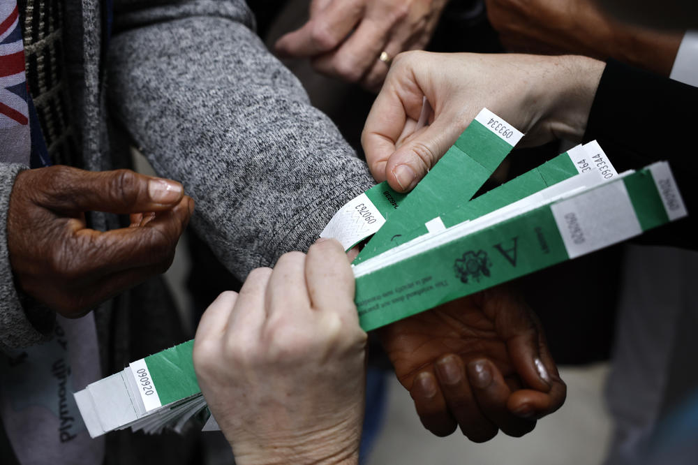 People put on the wristbands that indicate their place in line along Shad Thames while waiting in line to pay their respects to Queen Elizabeth.