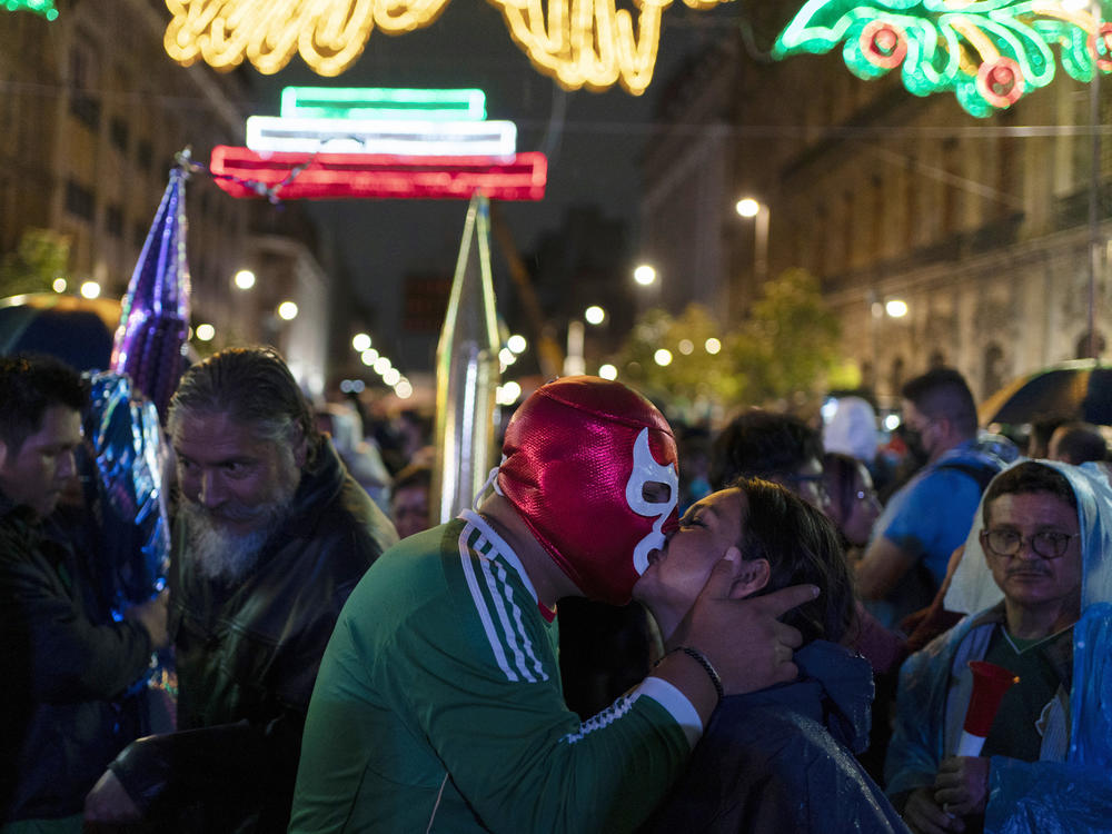 A man wearing a Lucha Libre wrestler's mask kisses a woman during the Independence Day celebrations at Mexico City's main square, the Zócalo.