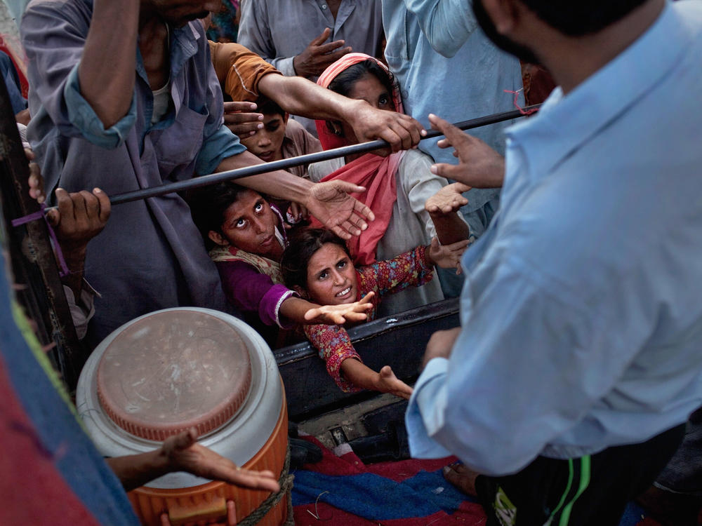 Children reach for food handouts in the aftermath of the catastrophic flooding in Pakistan, which has destroyed rice, corn and wheat crops and left over a third of the country under water.