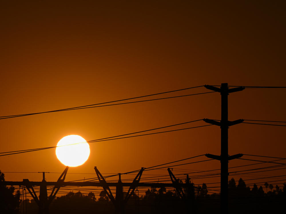 A spike in natural gas prices amid a hot summer is contributing to high electricity bills across the United States. Here, the sun sets behind electric power lines in Redondo Beach, Calif., on Aug. 31.