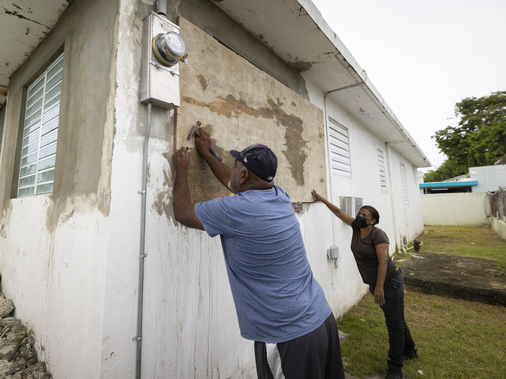 Residents attach protective plywood to a window of their home in preparation for the arrival of Tropical Storm Fiona, in Loiza, Puerto Rico, on Saturday.