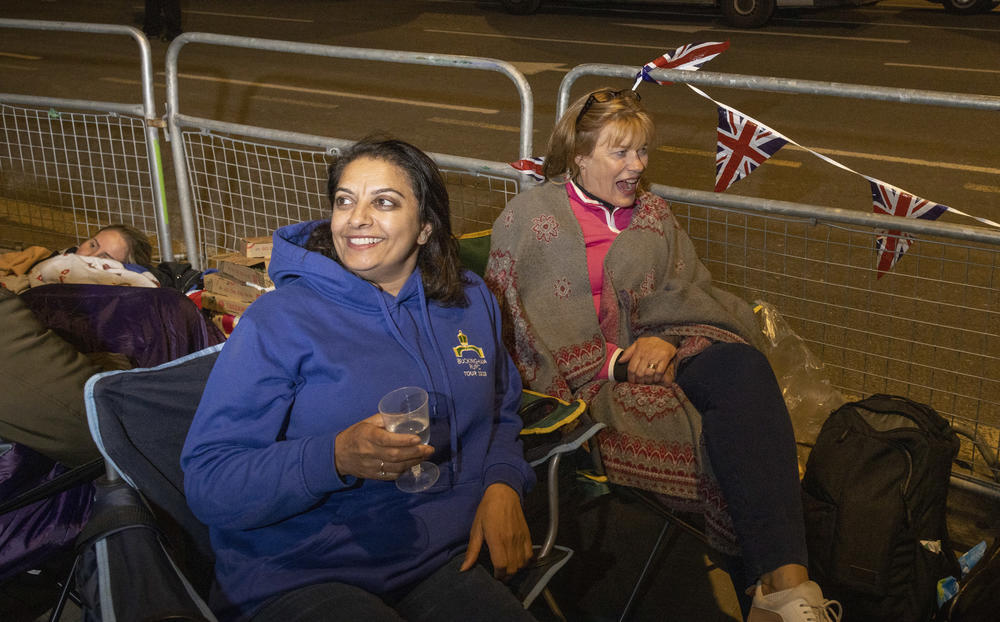 Hardish Purewal drinks a glass of fizzy next to her friend Loo Blackburn as they camp overnight outside of Westminster Hall and the houses of Parliament in London.