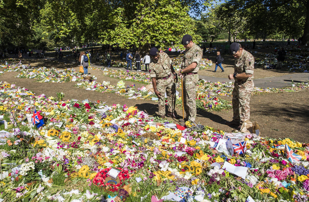 Graham Monks from the British Army looks at the Queen's official floral tribute area, along with other members of the British Army in Green Park, London Saturday.
