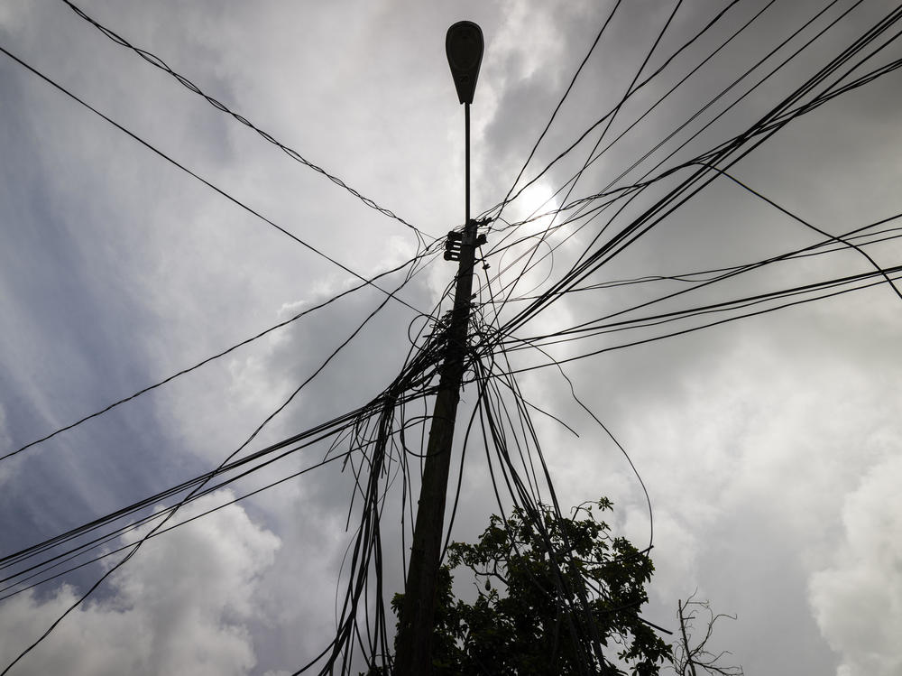 A utility pole with loose cables towers over a home in Loíza, Puerto Rico, on Sept. 15. Nearly five years have gone by since Hurricane Maria struck Puerto Rico, but the island's electrical infrastructure remains in deep disrepair.
