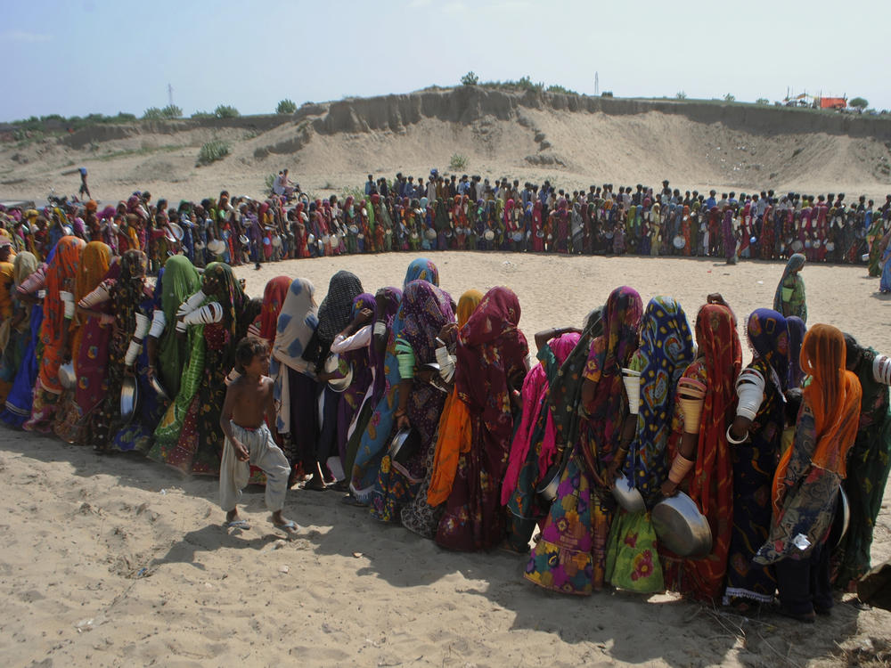 People wait in line for food in Sindh province, Pakistan, on Sept. 19, 2022. The province was one of the hardest hit by recent deadly floods. A new analysis confirms that climate change likely helped cause the disaster.