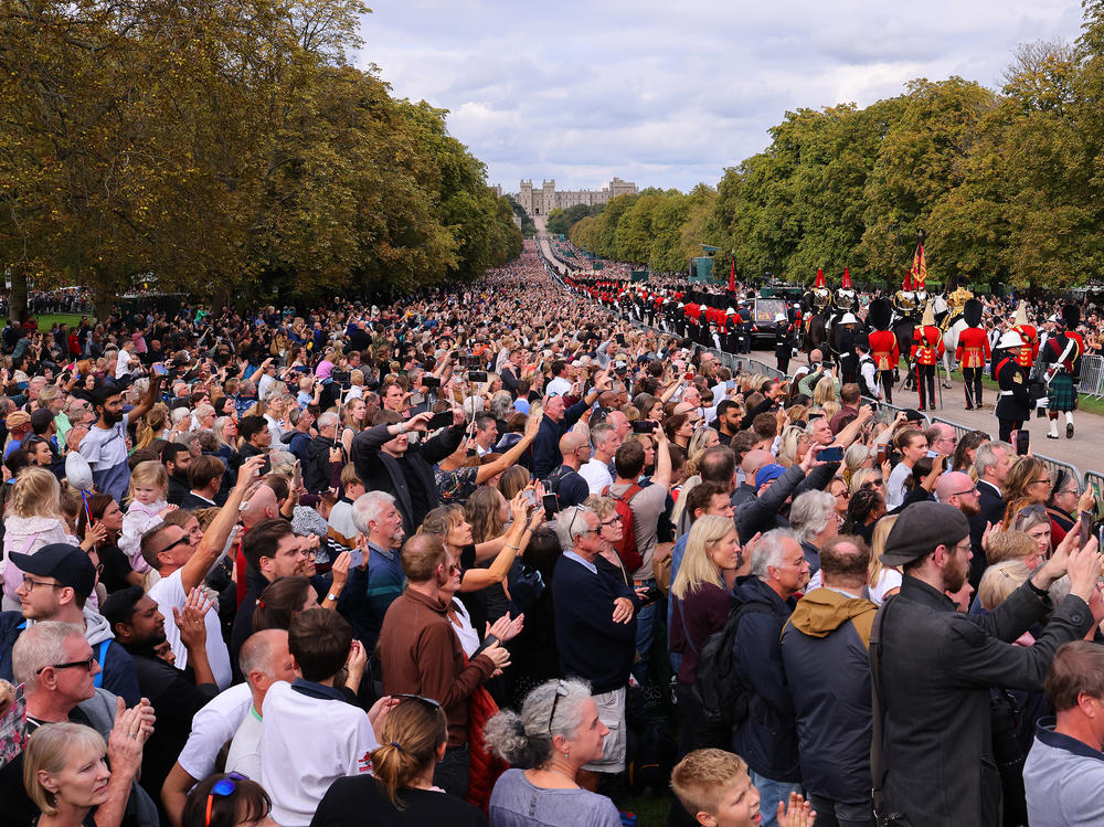 Mourners watch Queen Elizabeth's hearse as it drives along the Long Walk on Monday in Windsor, England. The committal service at Windsor Castle's St. George's Chapel took place following the state funeral at Westminster Abbey. A private burial in the King George VI Memorial Chapel followed.