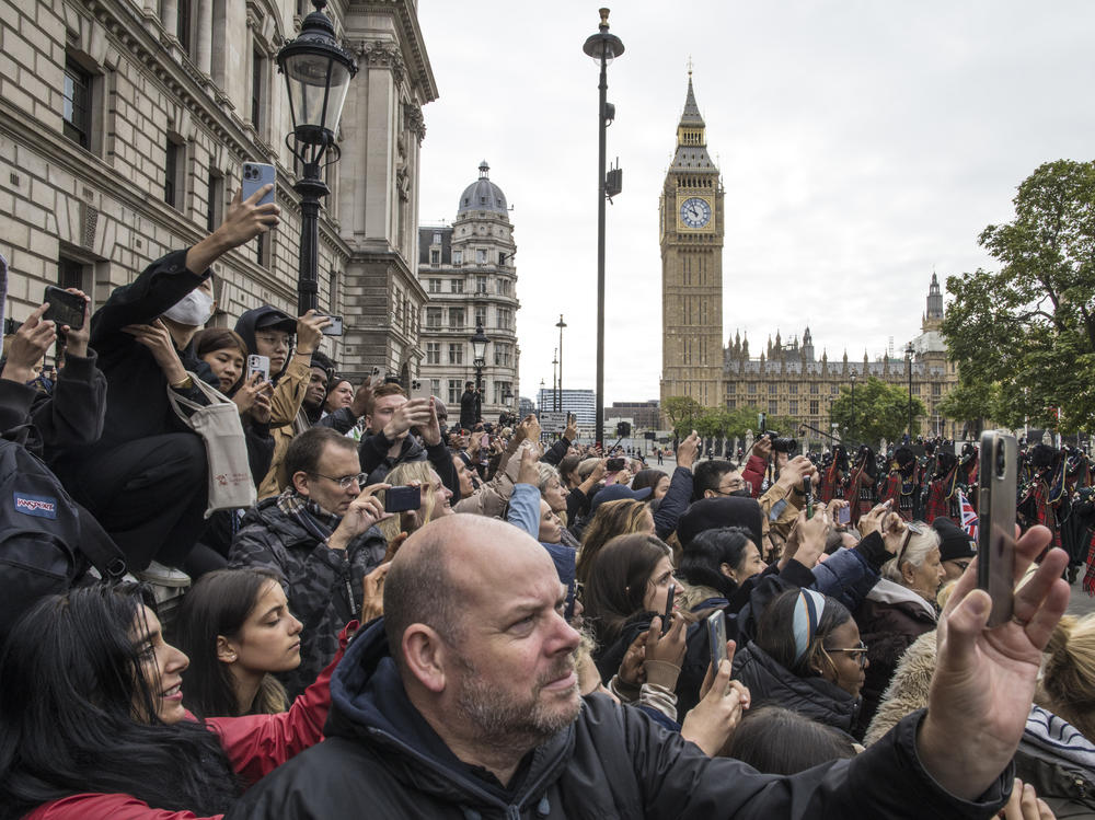 Mourners photograph the funeral procession as they gather to say goodbye to Queen Elizabeth II outside the Palace of Westminster and the houses of Parliament in London on Monday. The final leg of Monday's journey for Queen Elizabeth II, who served as the constitutional monarch of the United Kingdom for 70 years, follows a state funeral at Westminster Abbey and a procession through the city.