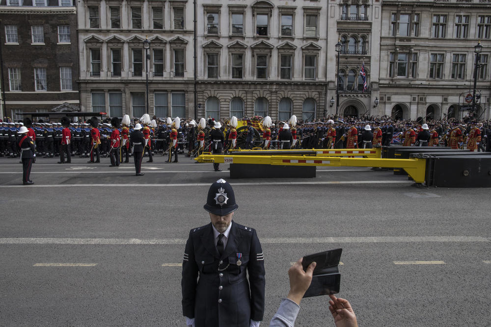 A spectator photographs the coffin of Queen Elizabeth II during the funeral procession for the late monarch as mourners gather to say goodbye outside the Palace of Westminster and the houses of Parliament in London on Monday.