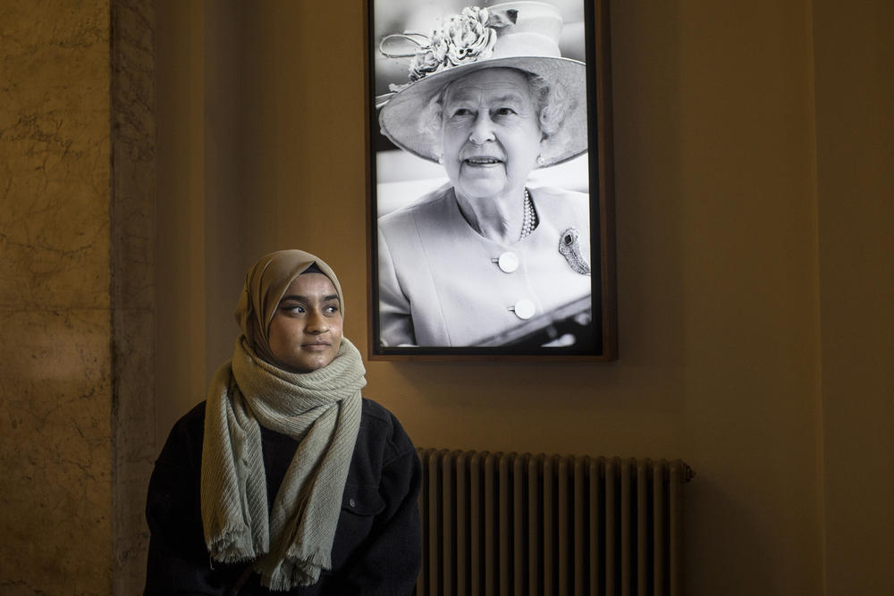 Atiya Chowdhury, 22, poses next to a picture of the late Queen Elizabeth II in London on Sunday.
