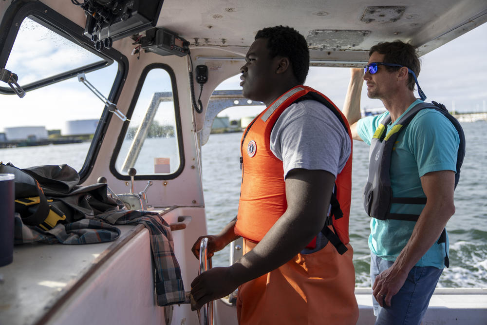 Cris is guided by Luke Holden while steering Sea Smoke.