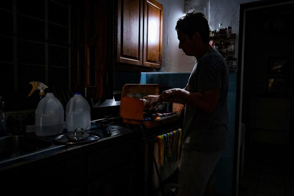 A person cooks in the dark in a home in the Condado community of Santurce in San Juan, Puerto Rico after Hurricane Fiona knocked out power.