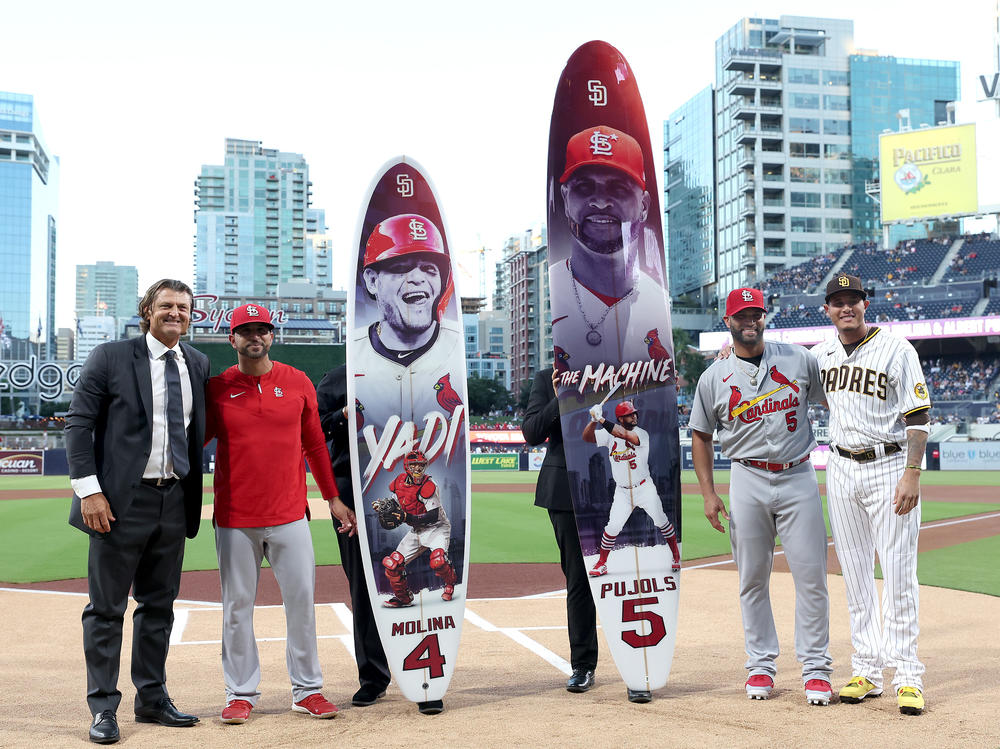 Retired MLB player Trevor Hoffman, St. Louis Manager Oliver Marmol, Albert Pujols and Manny Machado of the San Diego Padres pose for a photo with surfboards made to congratulate Yadier Molina #4 and Albert Pujols #5 on their pending retirements prior to Tuesday's game in San Diego.