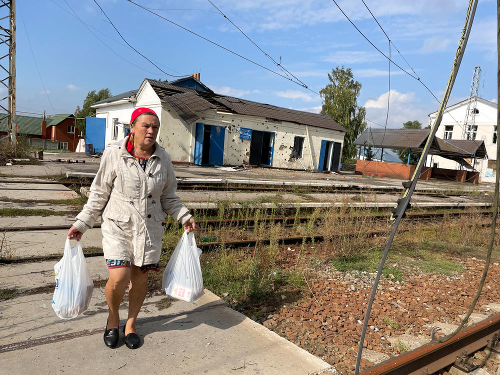 Luda Toryanyk, 58, walks across the railroad tracks in Kozacha Lopan, Ukraine, on Sunday. The village was retaken by Ukrainian troops on Sept. 11 after being occupied by Russian forces for more than six months. Toryanyk carries home bags of food that Ukrainian volunteers were distributing in the center of the village.