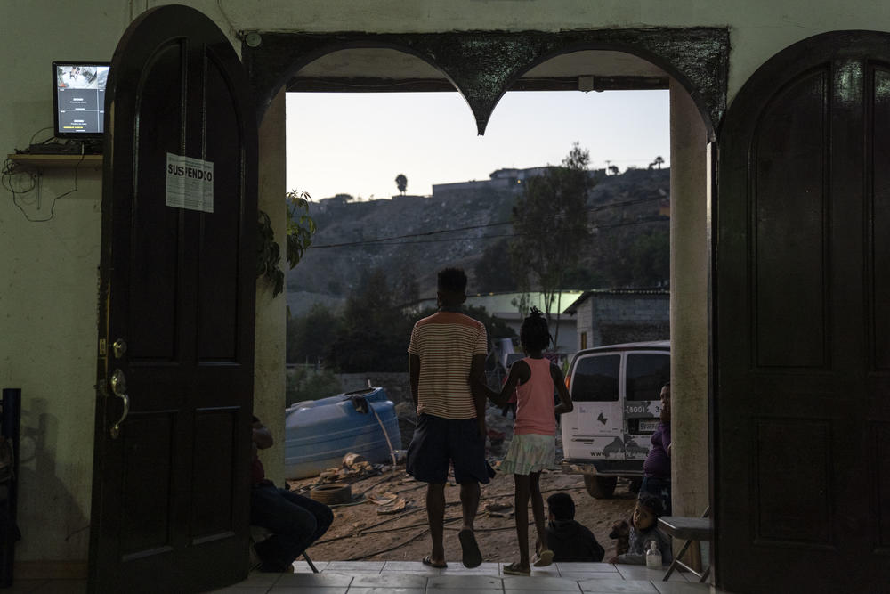 A father and daughter from Haiti step outside the Embajadores de Jesús shelter.