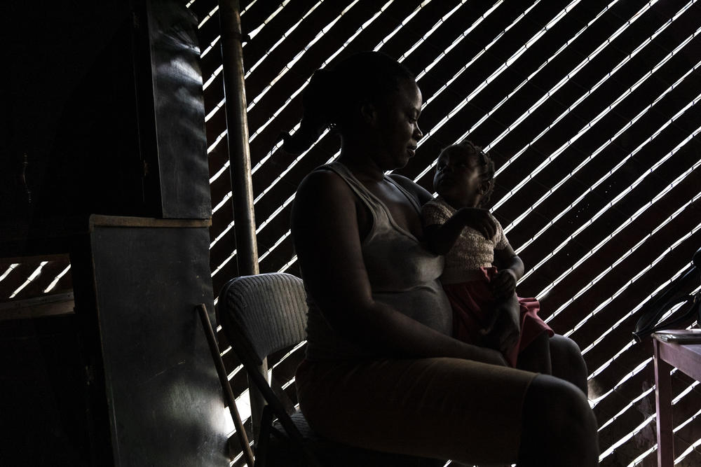 Una madre de Haití viste a su bebe en el albergue Embajadores de Jesus.