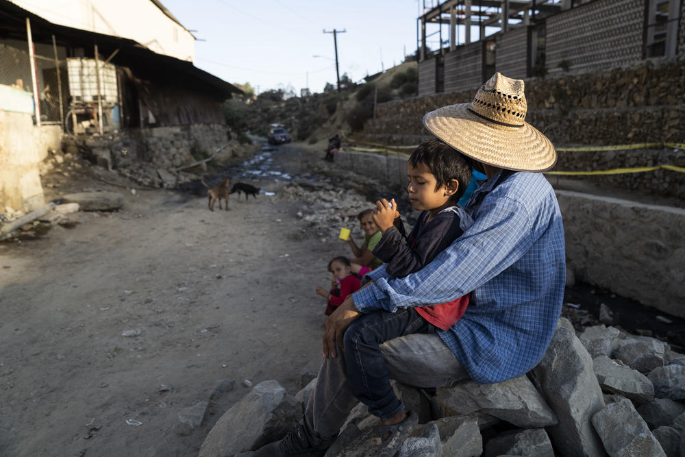 Abraham Lujano Pineda, 5, sits on his father's lap outside the Embajadores de Jesús shelter.