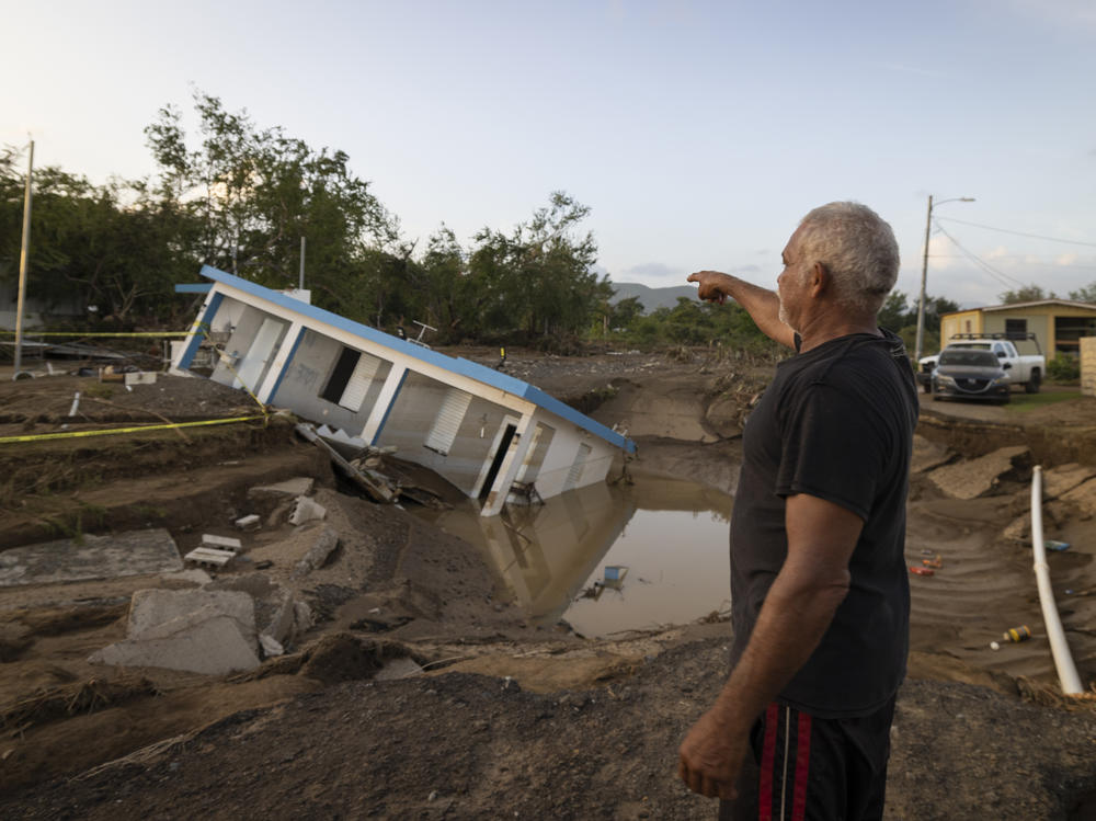 A man on Wednesday points to a home that was collapsed by Hurricane Fiona at Villa Esperanza in Salinas, Puerto Rico.