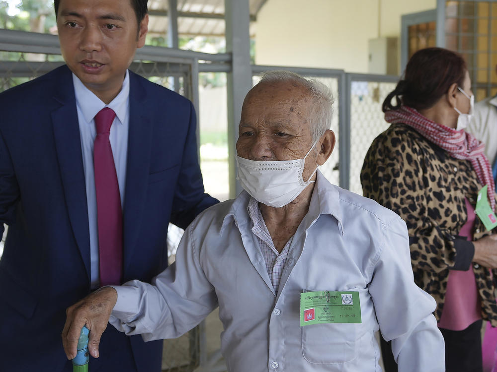 Bou Meng, second from left, former prison survivor, is helped into the courtroom before the hearings against Khieu Samphan, former Khmer Rouge head of state, in Phnom Penh, Cambodia, Thursday, Sept. 22, 2022.