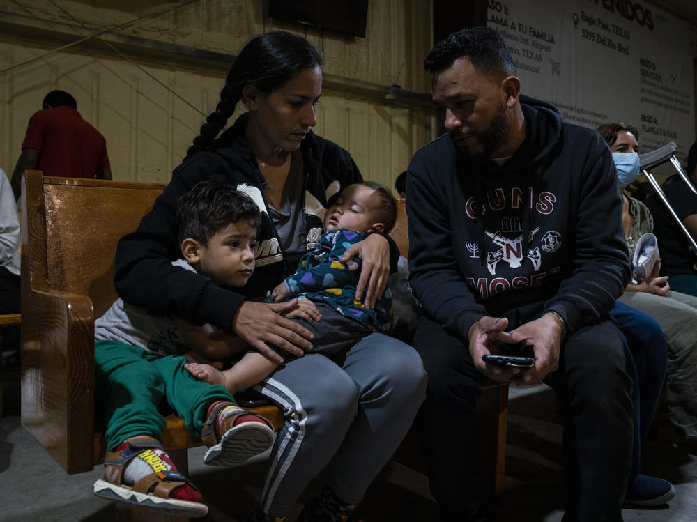 Venezuelan migrants Kimberly González and Denny Velasco and their children wait for a bus at Mission: Border Hope in Eagle Pass, Texas.