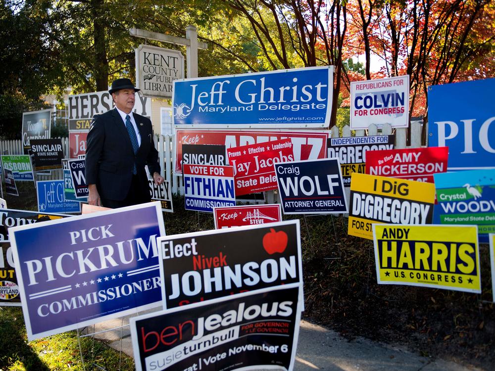 Mark Mumford, clerk of the Circuit Court for Kent County, Md., walks through a mass of political placards as he arrives to check on voter turnout in Maryland's early voting at the Kent County Public Library in Chestertown on Oct. 25, 2018.