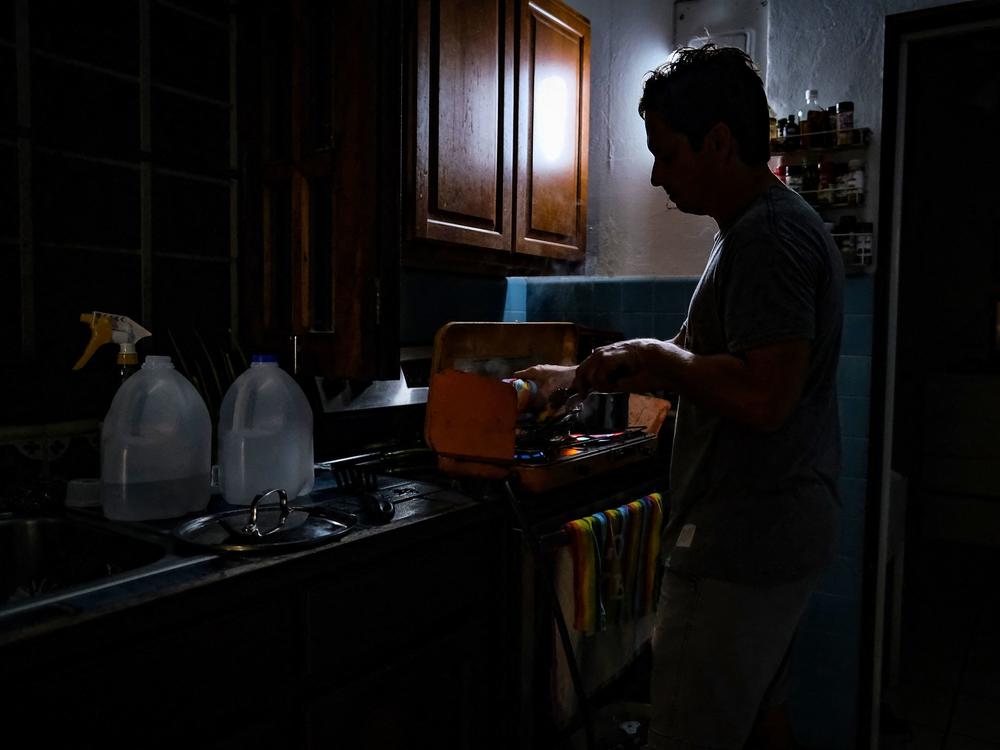 A person cooks in the dark in a home in the Condado community of Santurce in San Juan, Puerto Rico, after the the power went out.